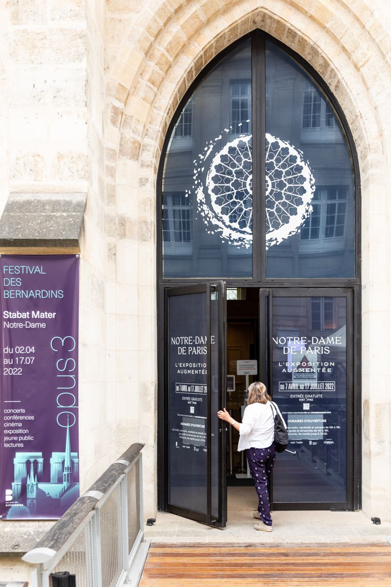 Entrée d’un bâtiment en pierre avec un motif circulaire blanc sur le vitrage.