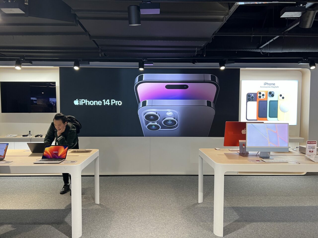 Grand visuel publicitaire rétroéclairé derrière des tables de présentation de téléphones.