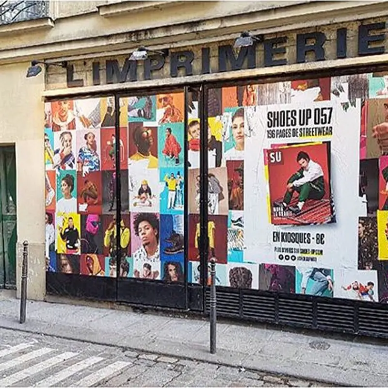 Façade de magasin recouverte d’affiches colorées sous une enseigne « L’Imprimerie ».