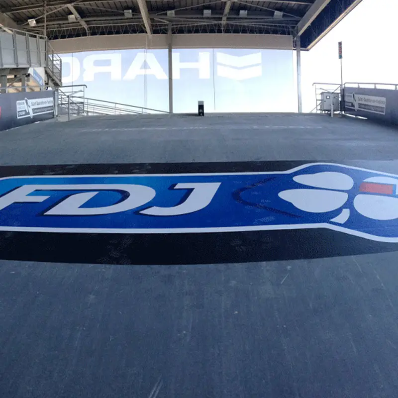Grand marquage de sol bleu portant le logo FDJ dans un espace couvert.