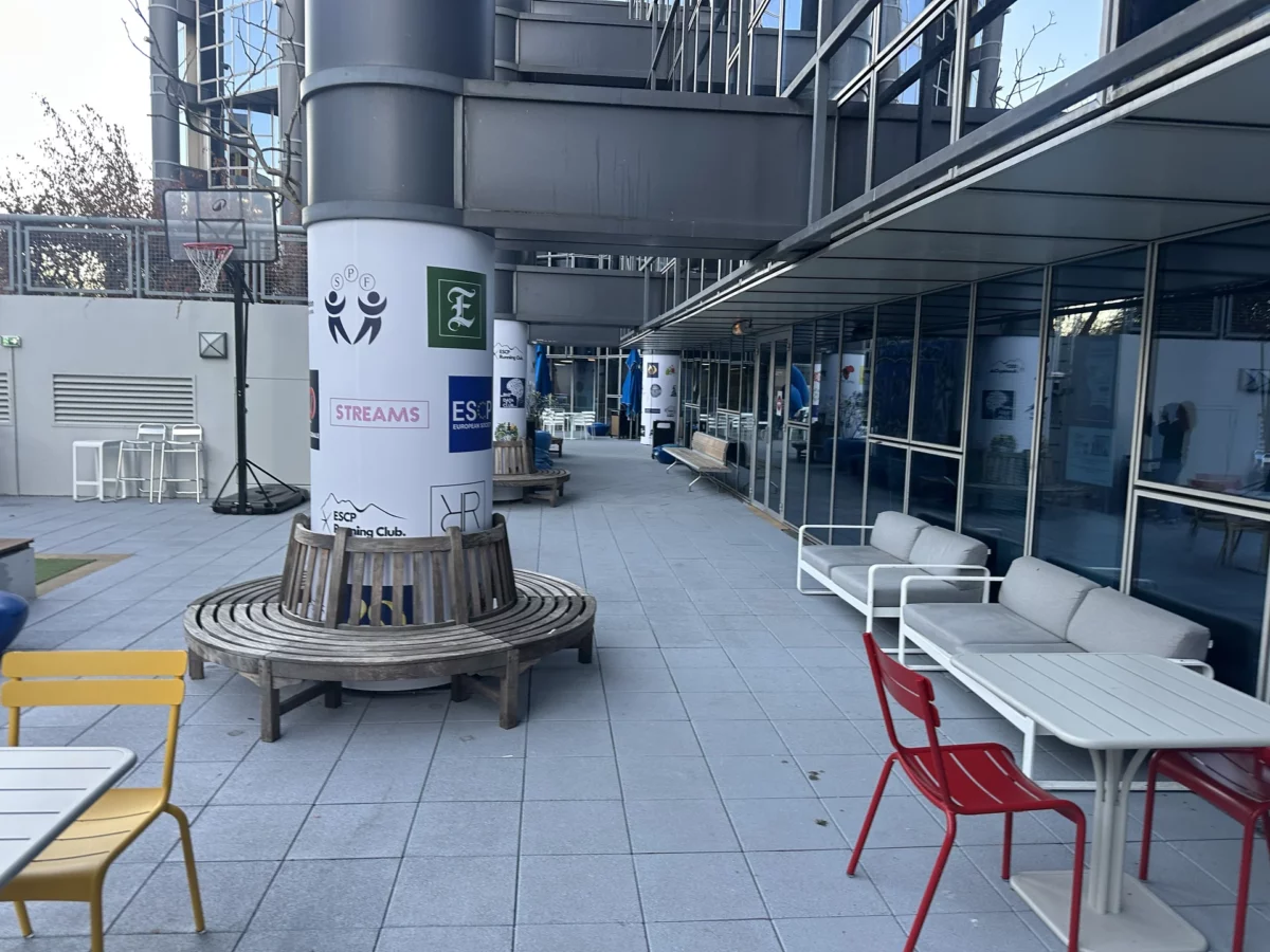 Vue latérale de la cour de l’ESCP Porte de Champerret avec les colonnes habillées de vinyles imprimés et les bancs circulaires.