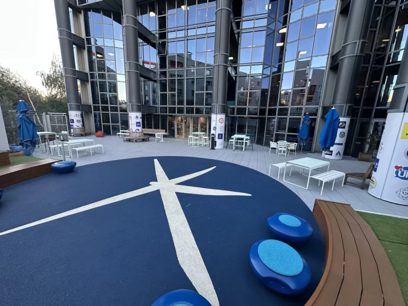 Vue de la cour de l’ESCP Porte de Champerret : grand marquage bleu et blanc au sol et colonnes habillées de vinyles imprimés.