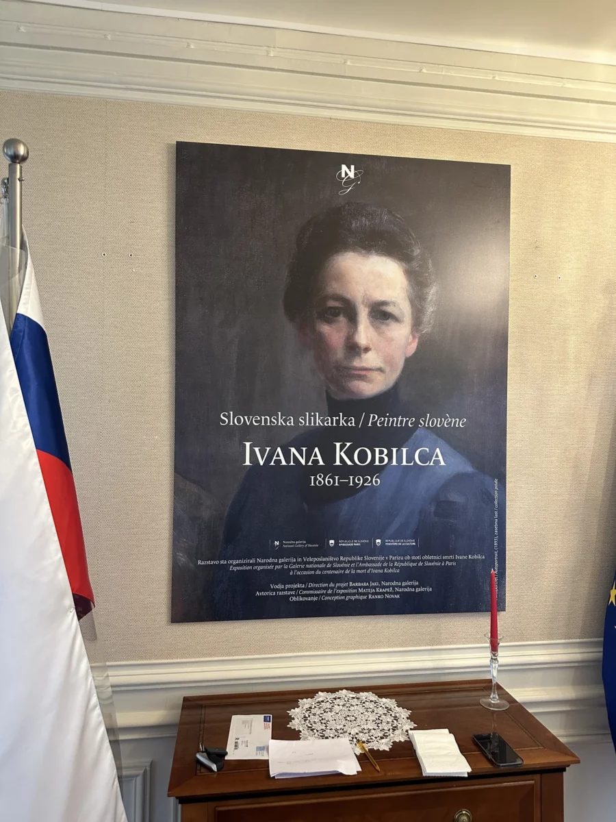 Panneau de présentation de l’exposition Ivana Kobilca, à côté du drapeau slovène, à l’ambassade de Slovénie à Paris.