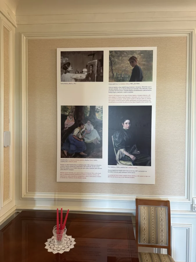 Panneau présentant plusieurs œuvres d’Ivana Kobilca au-dessus d’une table dans un salon de l’ambassade de Slovénie.