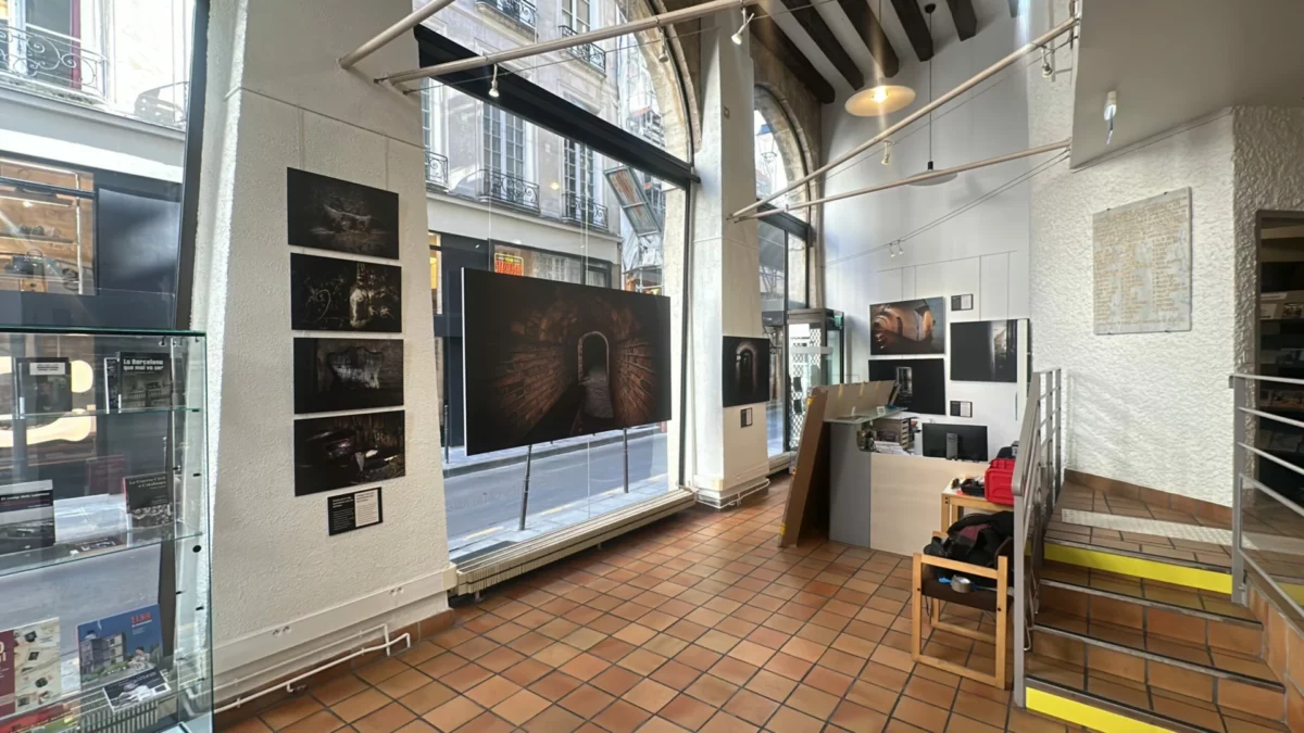 Vue intérieure de la salle avec les photographies exposées le long de la vitrine.