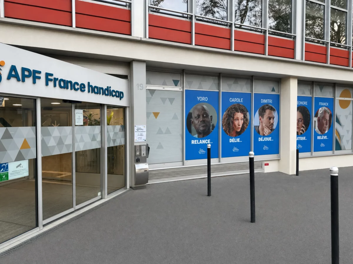 Entrée d’APF France handicap et alignement des bâches imprimées posées sur la façade à Paris.