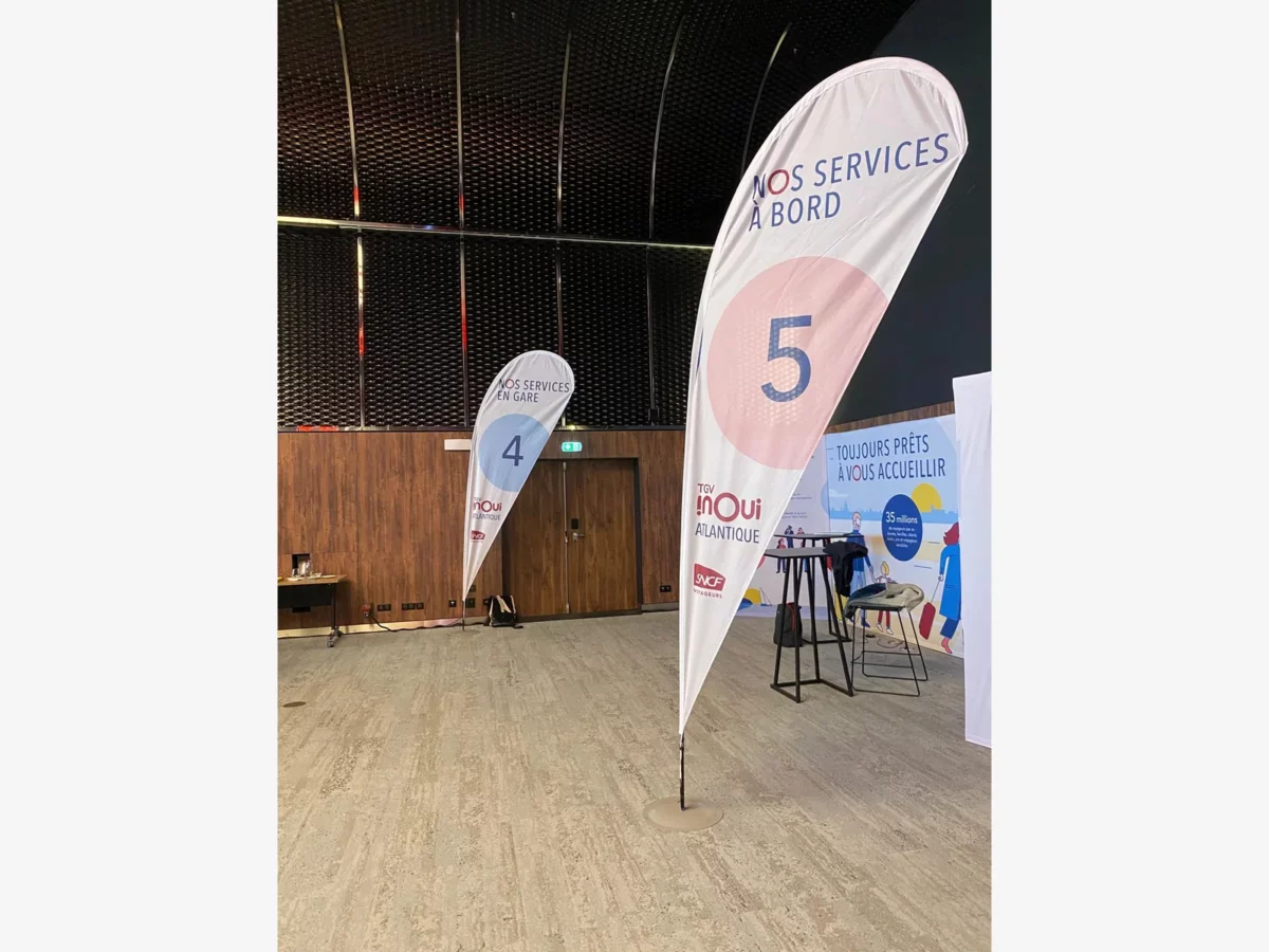 Drapeaux goutte numérotés 4 et 5, installés pour signaler les espaces services en gare et services à bord.